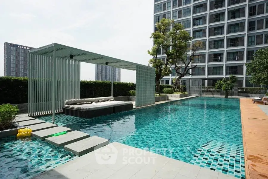 Luxurious apartment complex with modern pool and lounging area, perfect for relaxation and leisure.