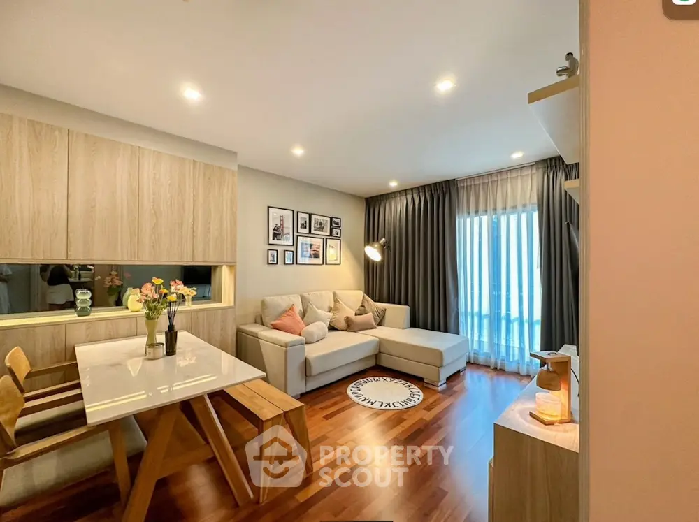 Modern living room with cozy sectional sofa and dining area, featuring elegant wood flooring and stylish decor.