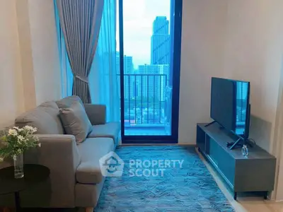 Cozy living room with city view, featuring a plush sofa and modern TV setup.