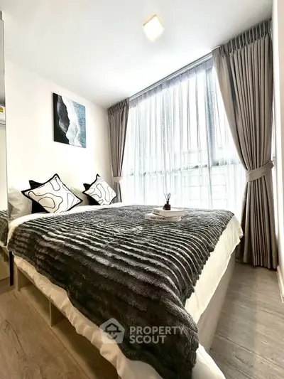 Modern bedroom with large window and stylish decor in a bright apartment.