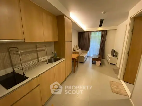 Modern open-layout kitchen and living room with sleek wooden cabinetry and cozy seating area.