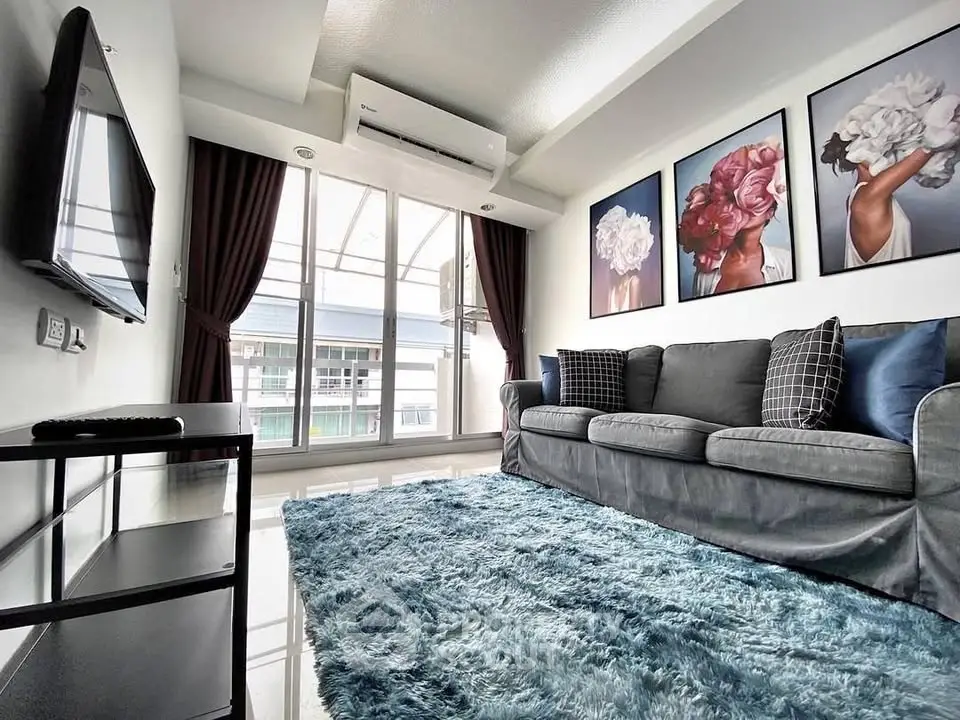 Modern living room with stylish decor, plush sofa, and large window offering natural light.