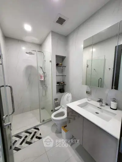 Modern bathroom with glass shower, sleek vanity, and elegant tile design.