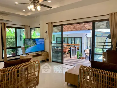 Spacious living room with modern decor and large windows opening to a patio with outdoor seating.
