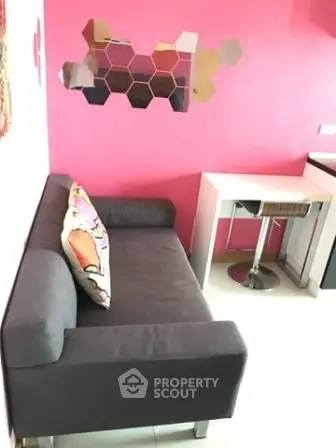 Chic modern living room with vibrant pink accent wall and stylish gray sofa.