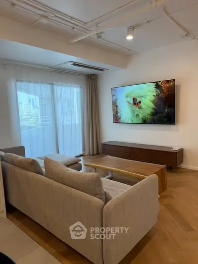 Modern living room with large TV and cozy sofa, featuring a bright and airy atmosphere with city view.
