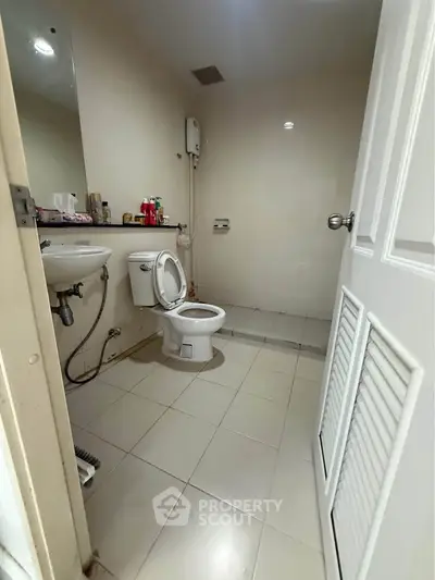 Compact bathroom with essential fixtures and neutral tiles, ideal for small spaces.