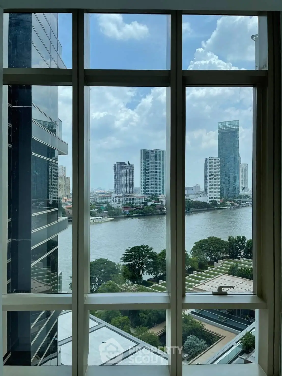 Stunning river view from high-rise building window showcasing urban skyline and lush greenery.