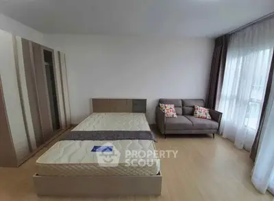 Spacious bedroom with modern furniture and large window for natural light.