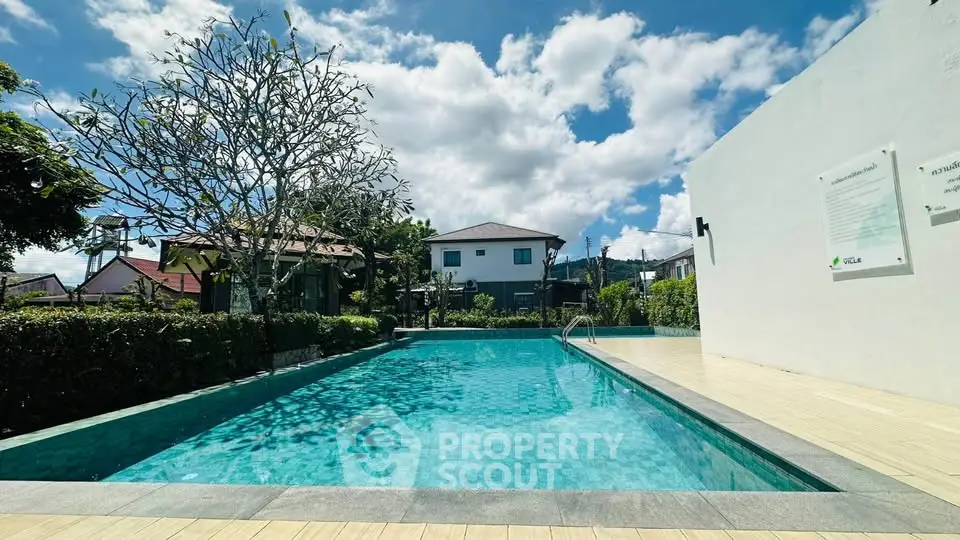 Stunning residential pool area with clear blue water and lush greenery under a bright sky.