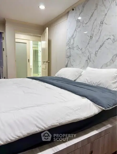 Luxurious bedroom with elegant marble accent wall and cozy bedding