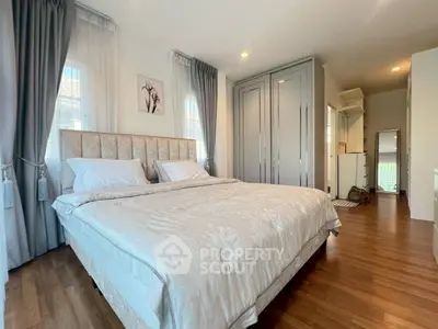 Spacious bedroom with elegant decor and ample natural light, featuring a large bed and stylish wooden flooring.