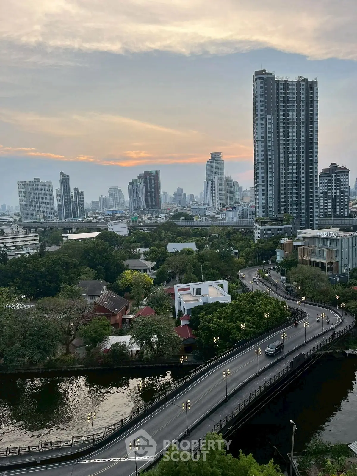 Stunning cityscape view with high-rise buildings and lush greenery at sunset.