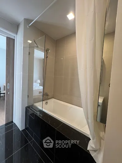 Modern bathroom with sleek bathtub and glass shower partition in luxury apartment
