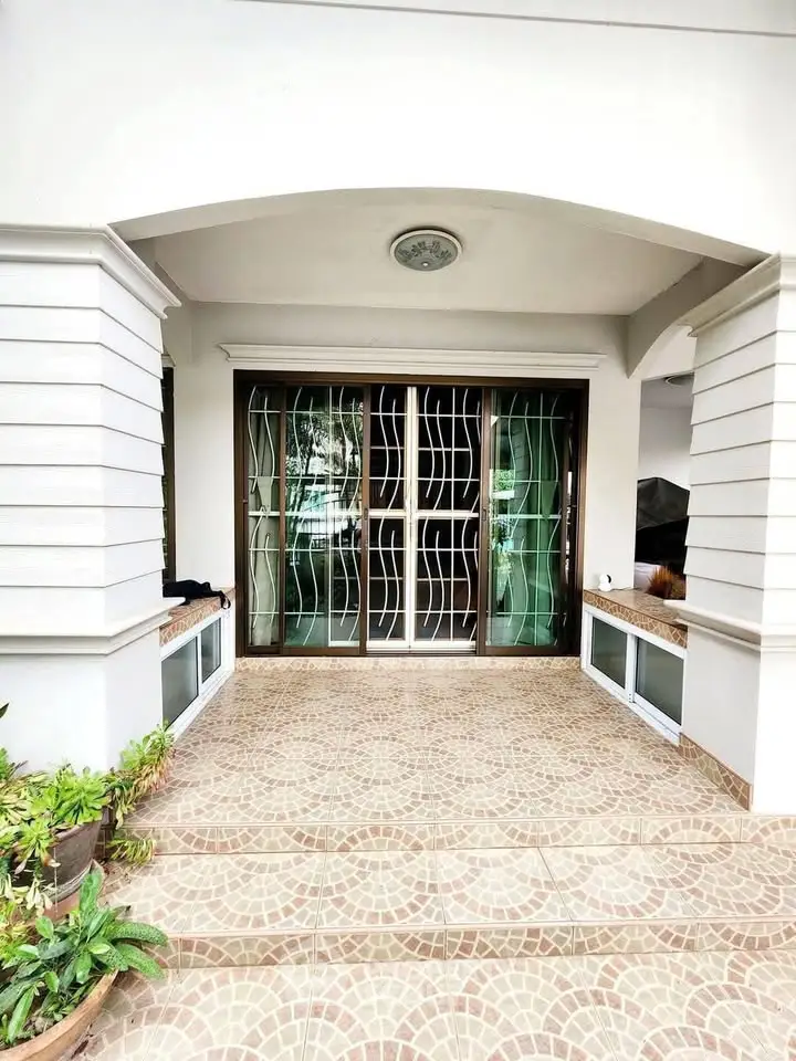 Elegant entrance with decorative iron doors and tiled flooring, perfect for a welcoming home facade.