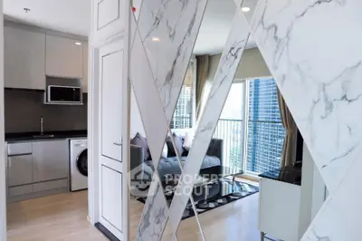 Sleek modern kitchen with high-end appliances and marble accents opens to a cozy living area with city views, perfect for urban living.