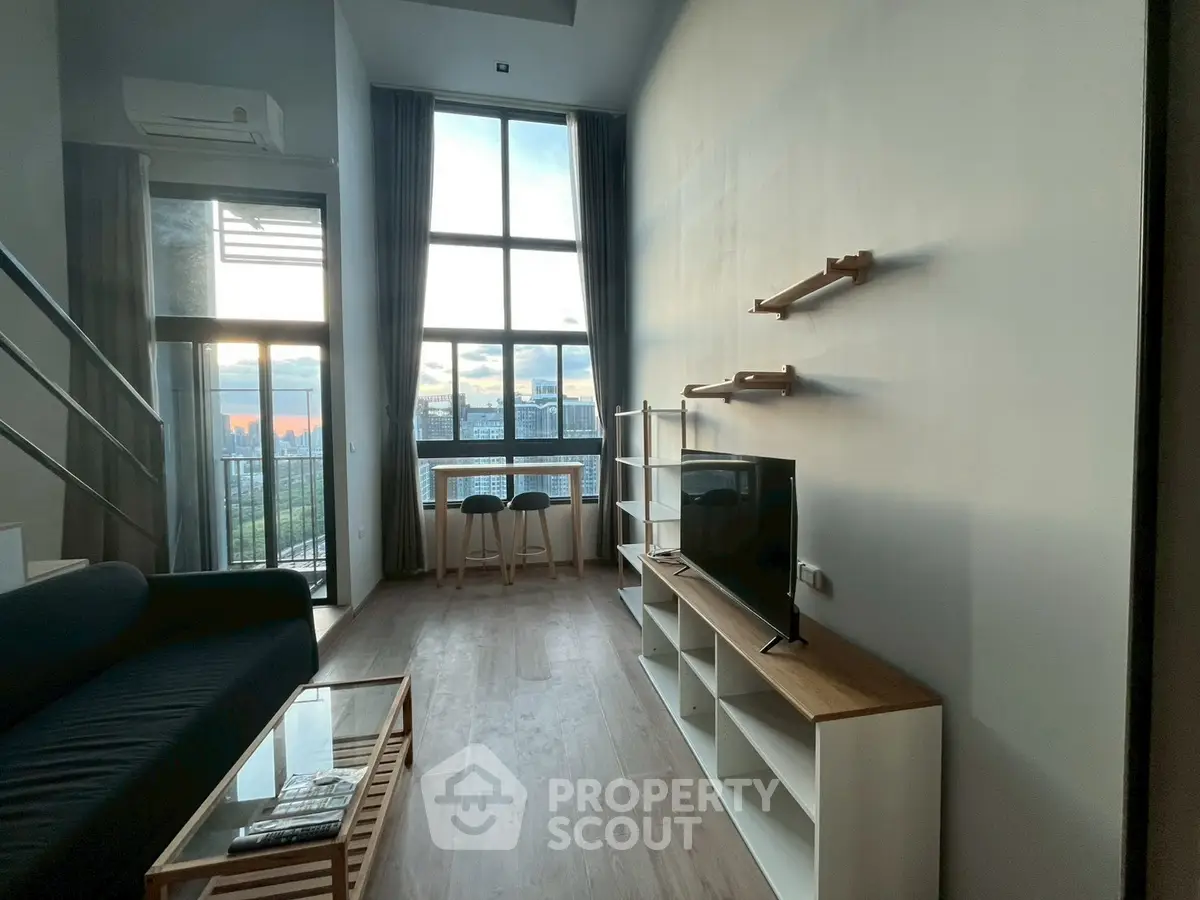 Modern living room with high ceiling and large windows offering stunning city views.