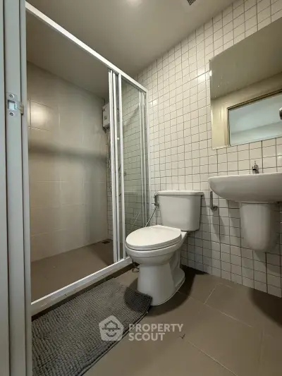 Modern bathroom with shower enclosure and sleek fixtures in a contemporary apartment.