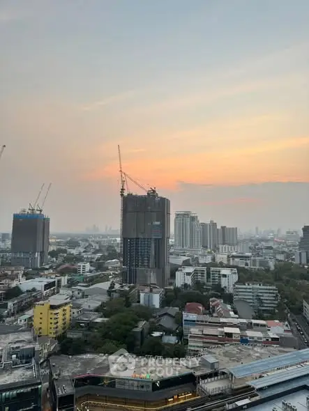 Stunning cityscape view with high-rise buildings and cranes at sunset.