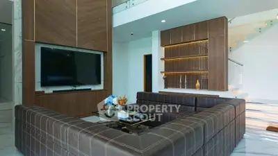 Luxurious modern living room with elegant brown sectional sofa and large flat-screen TV, perfect for relaxation.