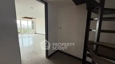 Spacious apartment with spiral staircase and large windows offering city views.