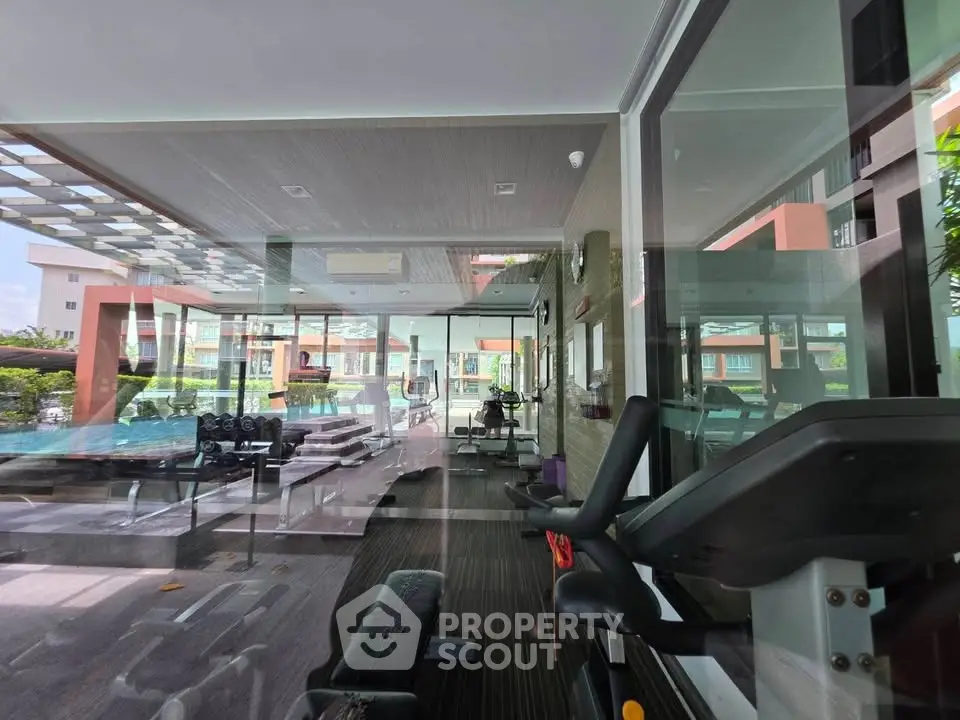 Modern gym with state-of-the-art equipment and pool view in luxury residential complex.