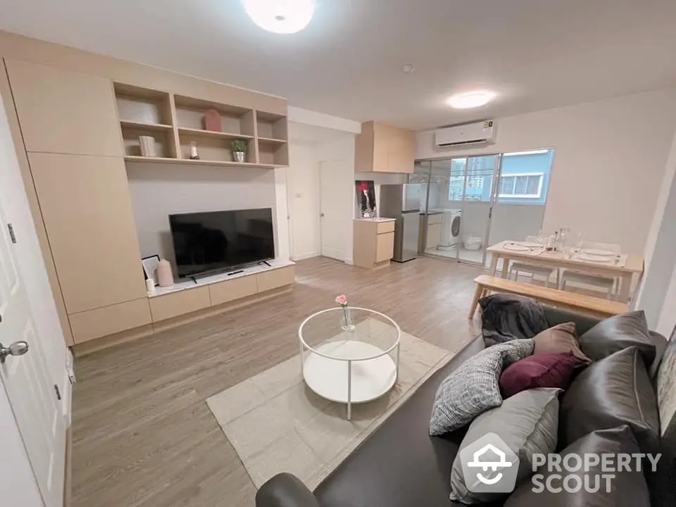 Spacious modern living room seamlessly connected to a sleek open layout kitchen, featuring contemporary furnishings and ample natural light.