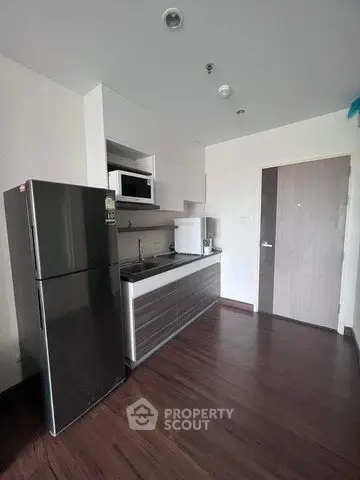 Modern kitchen with sleek appliances and dark wood flooring in a stylish apartment.