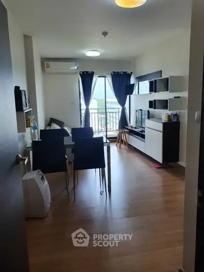 Modern living room with balcony view, stylish furniture, and wooden flooring in a contemporary apartment.