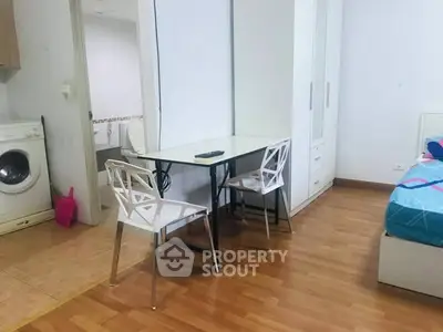 Cozy bedroom with dining area and washing machine, perfect for compact living.