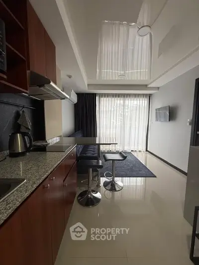 Modern kitchen with sleek design and open layout, featuring granite countertops and stylish bar stools.