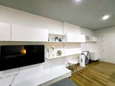 Modern living room with sleek white cabinetry and wall-mounted TV in a stylish apartment.