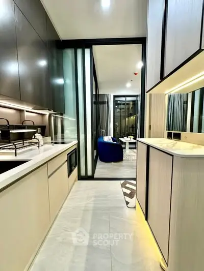 Modern kitchen with sleek cabinetry and open layout leading to a stylish living room.