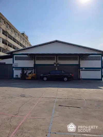 Industrial warehouse exterior with parking space and forklift