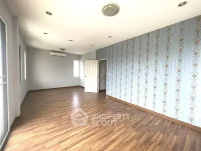 Spacious empty room with elegant wallpaper and wooden flooring, perfect for customization.