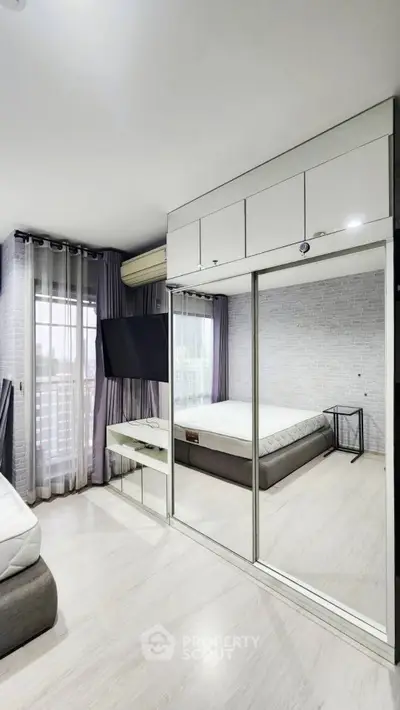 Modern bedroom with mirrored wardrobe and large window for natural light