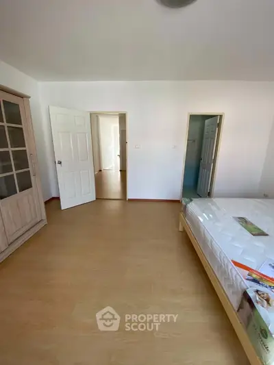 Spacious bedroom with wooden flooring and ample natural light