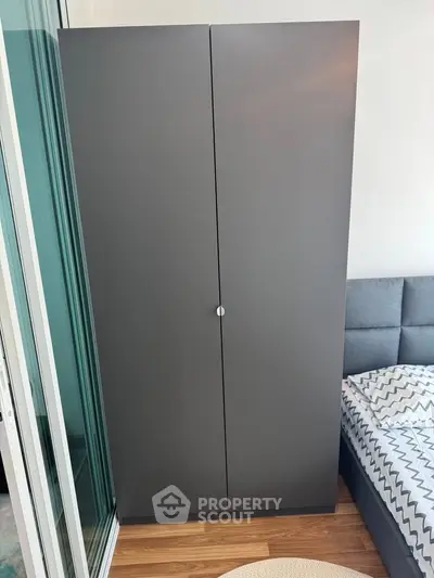 Modern bedroom with sleek wardrobe and stylish bed near glass doors.