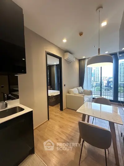 Modern open-plan living room with kitchen and balcony view in urban apartment.