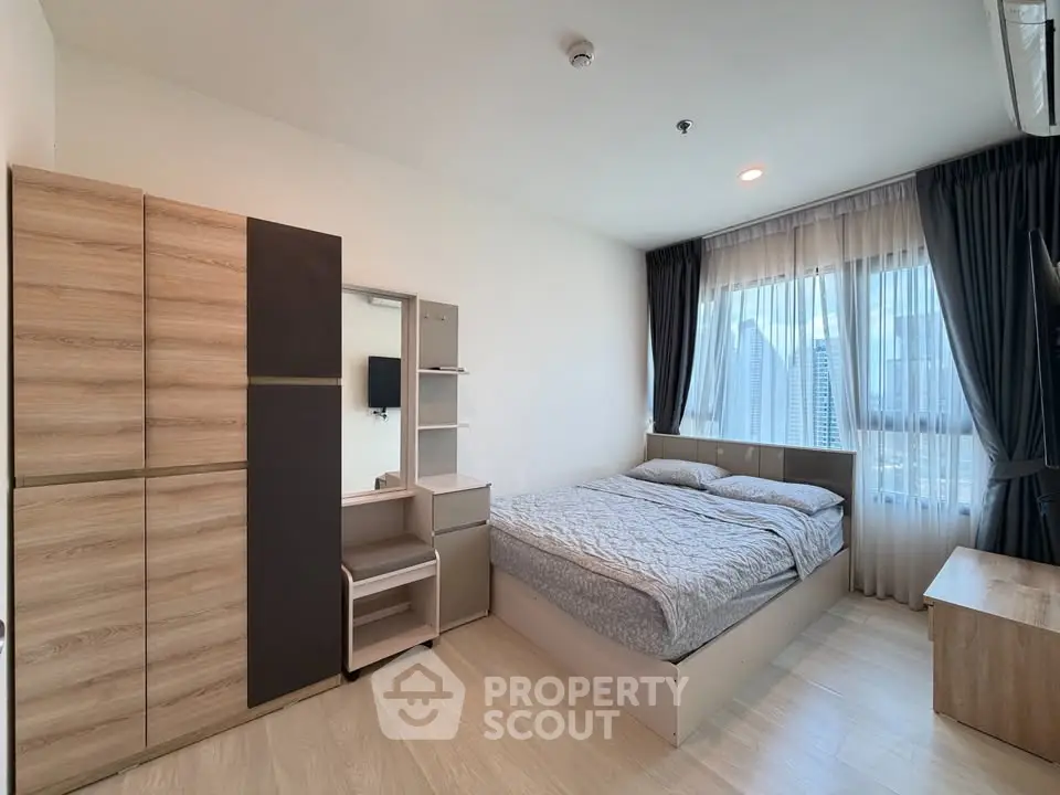 Modern bedroom with city view, featuring sleek furniture and natural light.