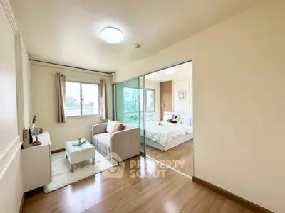 Modern apartment with cozy living room and bright bedroom, featuring sliding glass doors and wooden flooring.