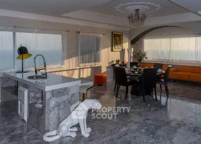 Luxurious open-plan living room with marble floors, modern kitchen island, and panoramic ocean views.