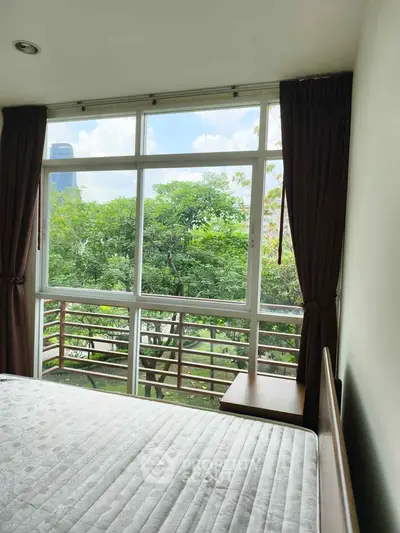Bright bedroom with large window and lush green view, perfect for nature lovers.