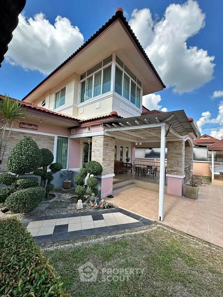 Charming two-story house with landscaped garden and spacious patio under a clear blue sky.