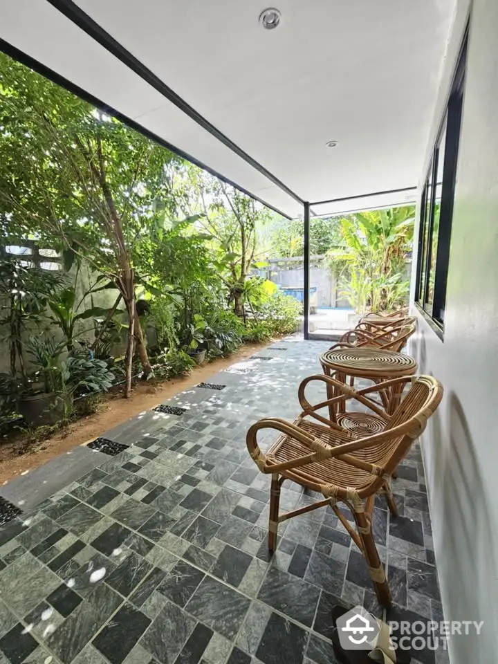 Charming garden patio with stylish rattan chairs and lush greenery, perfect for relaxation and outdoor enjoyment.