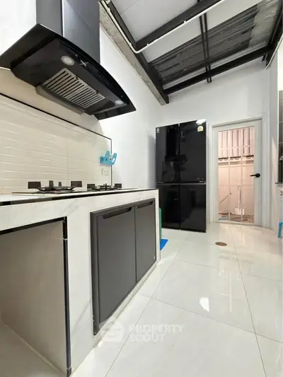Modern kitchen with sleek black appliances and open layout, featuring a gas stove and spacious design.