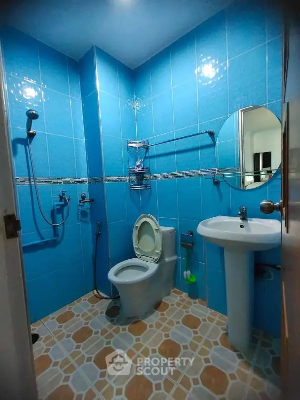 Modern blue-tiled bathroom with shower and pedestal sink