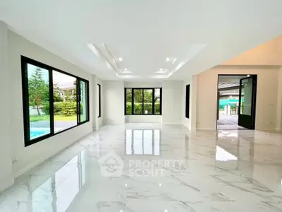 Spacious modern living room with large windows and glossy tile flooring, offering a bright and airy ambiance.