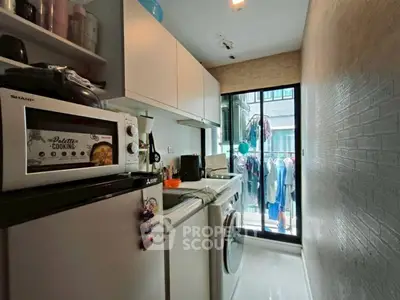 Compact kitchen with modern appliances and laundry area in urban apartment
