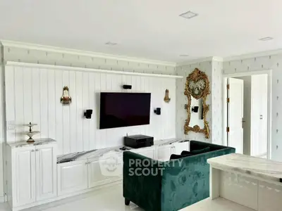 Luxurious living room with elegant decor, featuring a plush green sofa, wall-mounted TV, and ornate mirror.